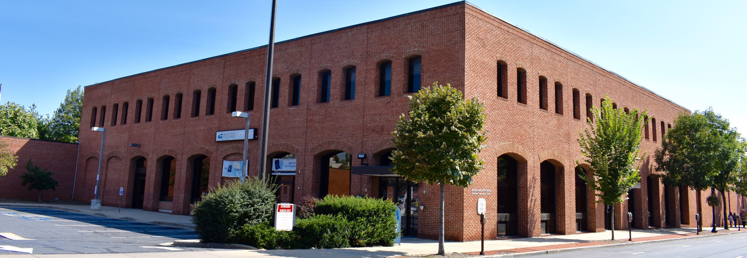 A red bricked building is featured here. Trees are planted around the building.